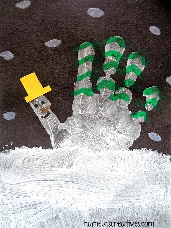 Une montagne d'hiver en empreinte de main avec bonhomme de neige et sapins